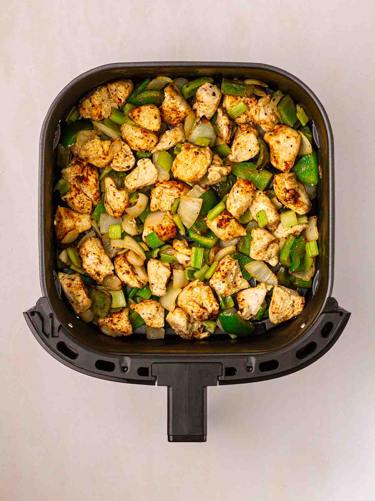 An air fryer filled with cooked cajun chicken dish, ready to serve.