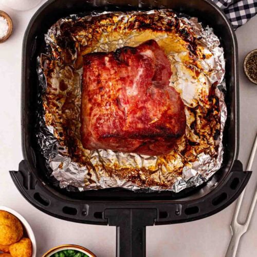 Air Fryer Gammon in an air fryer tray, ready to serve at the table alongside peas and potatoes.