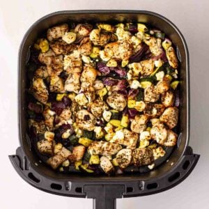 An air fryer with a Greek Chicken Traybake inside.