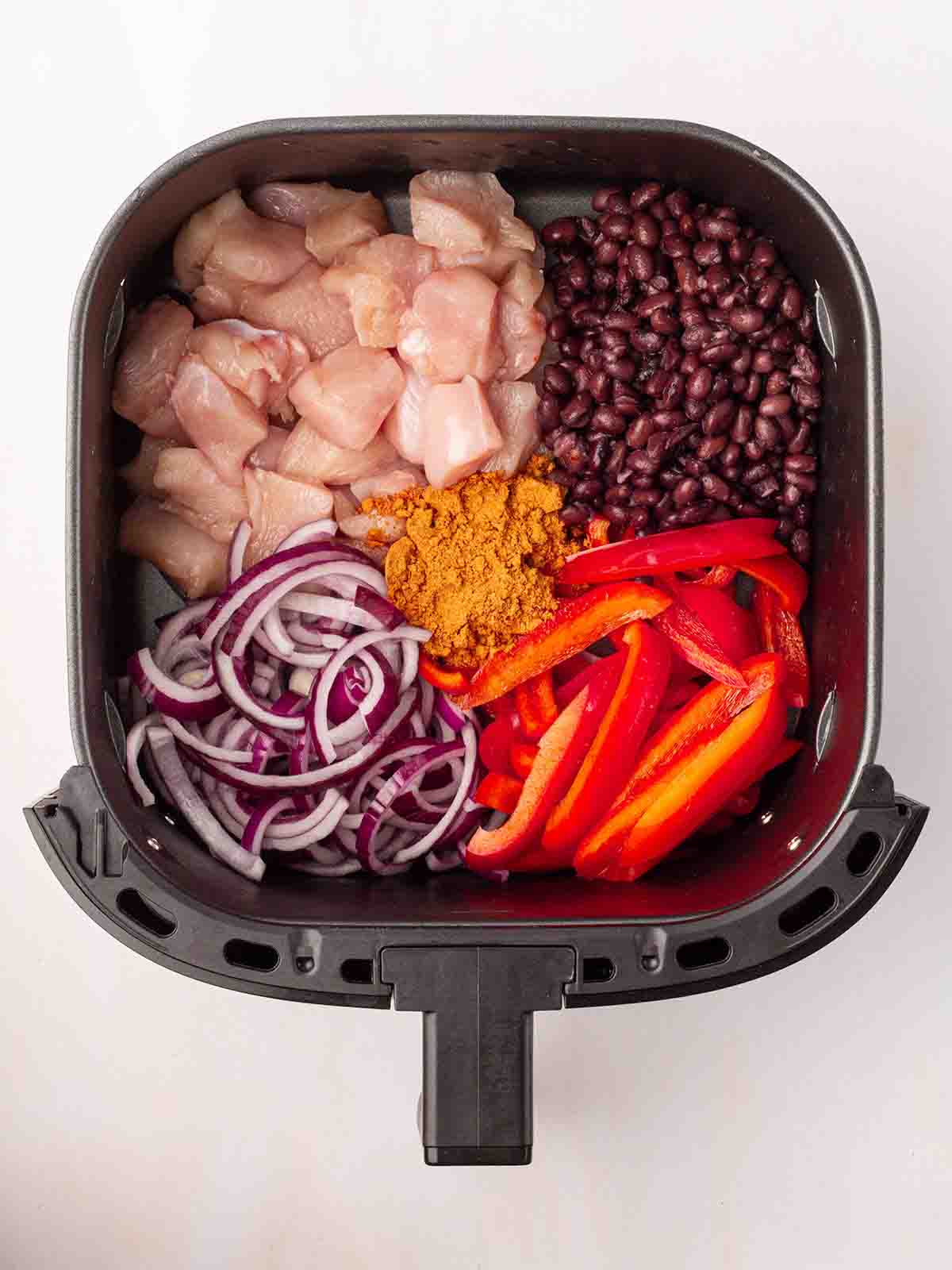 The raw ingredients for Air Fryer Mexican Chicken inside the air fryer, ready to cook.