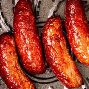 A close up of cooked sausages in an air fryer pan.