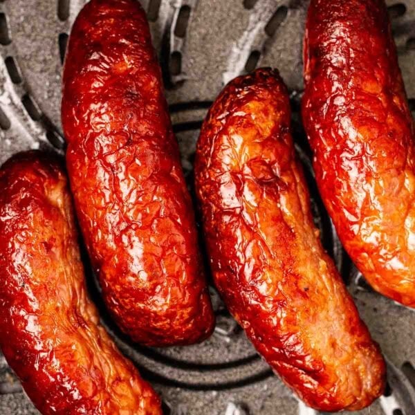 A close up of cooked sausages in an air fryer pan.