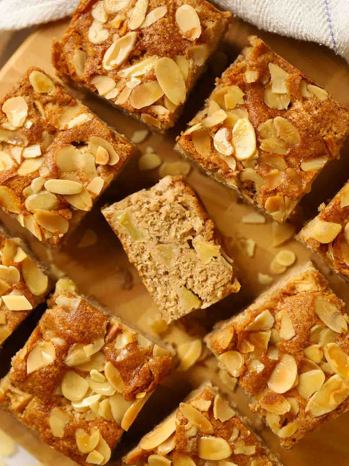Six small squares of apple cake on a board.