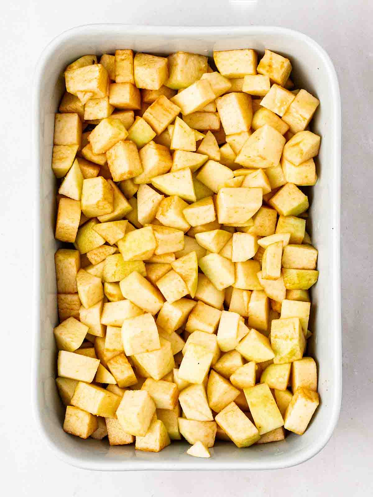 Cubed apples in a baking dish for step 1 in the recipe for Apple Crumble.