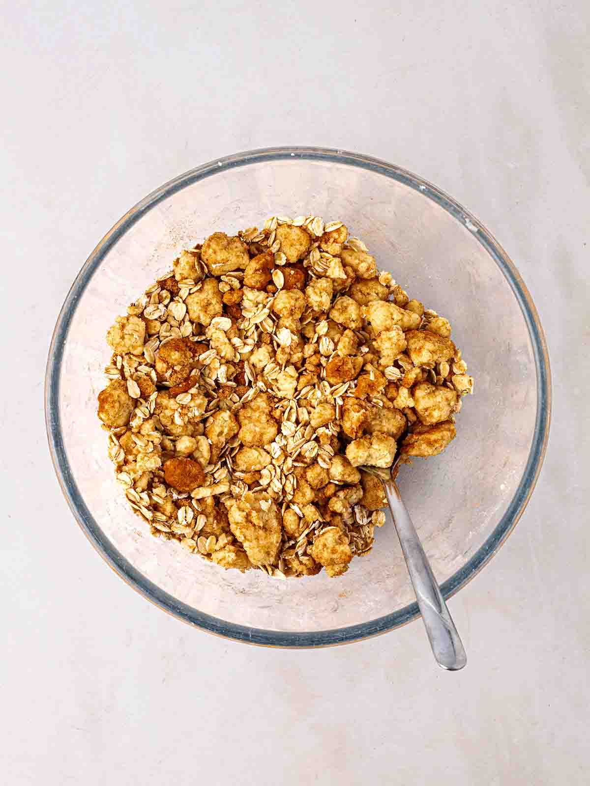 A glass bowl with oats and crumble inside for step 3 in the recipe for Apple Crumble.