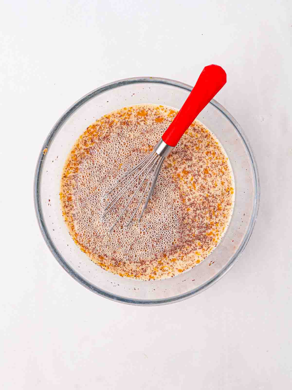 A glass bowl filled with egg and milk mixture for step 2 in the recipe for Bread and Butter Pudding.