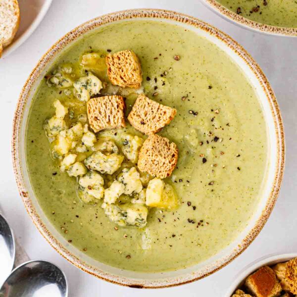 A big bowl of Broccoli and Stilton Soup on a white table.