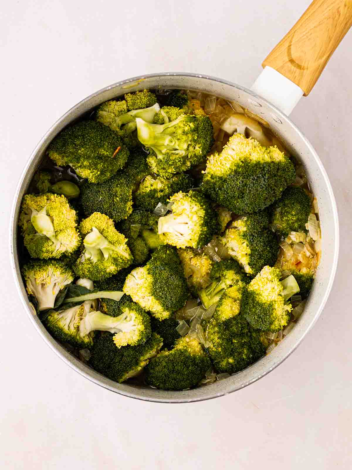 A pan filled with broccoli and onions for Broccoli and Stilton Soup recipe.