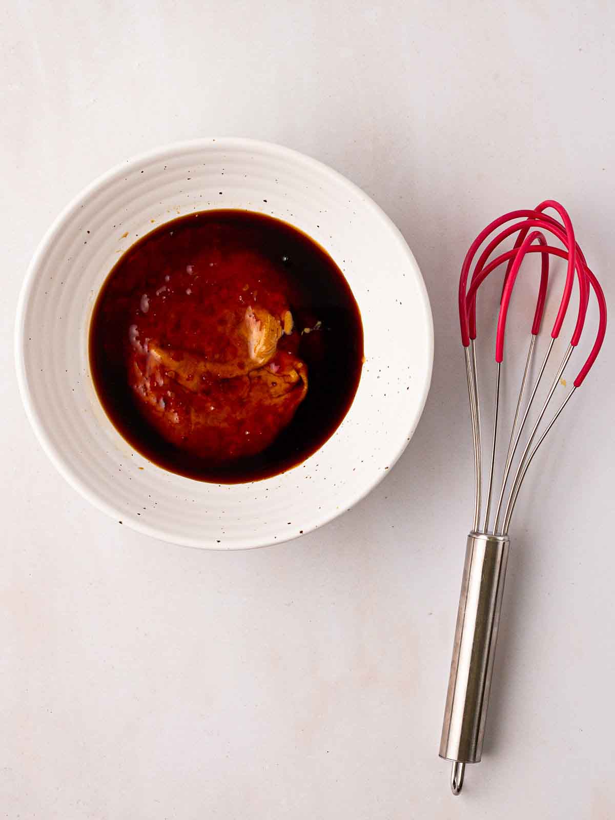 Peanut butter and soy sauce in a bowl with a whisk to the side for a Cabbage Salad dressing.