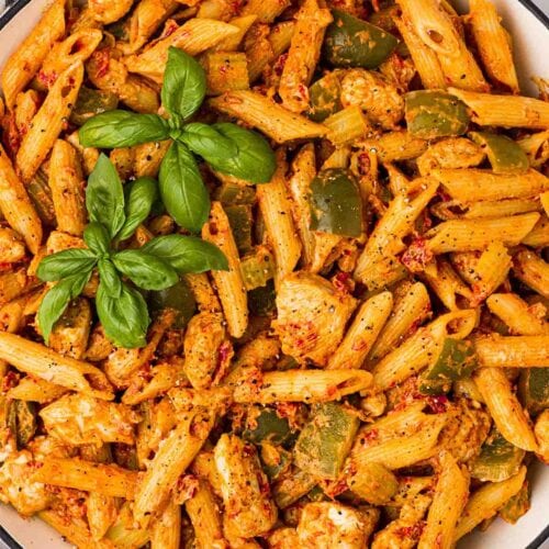 A bowl of Cajun Chicken Pasta, topped with basil leaves.