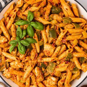 A bowl of one pan Cajun Chicken Pasta, ready to serve, with basil on top.