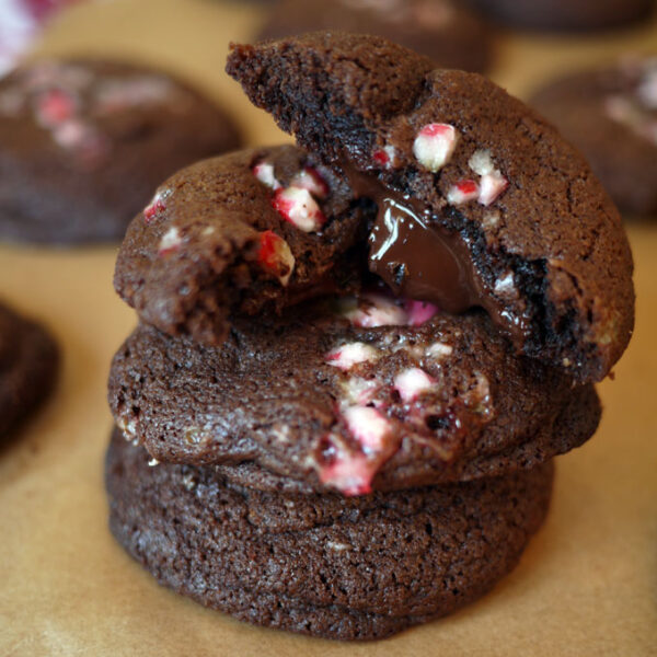 Piled up chocolate candy cane cookies, with one halved with a melting middle.