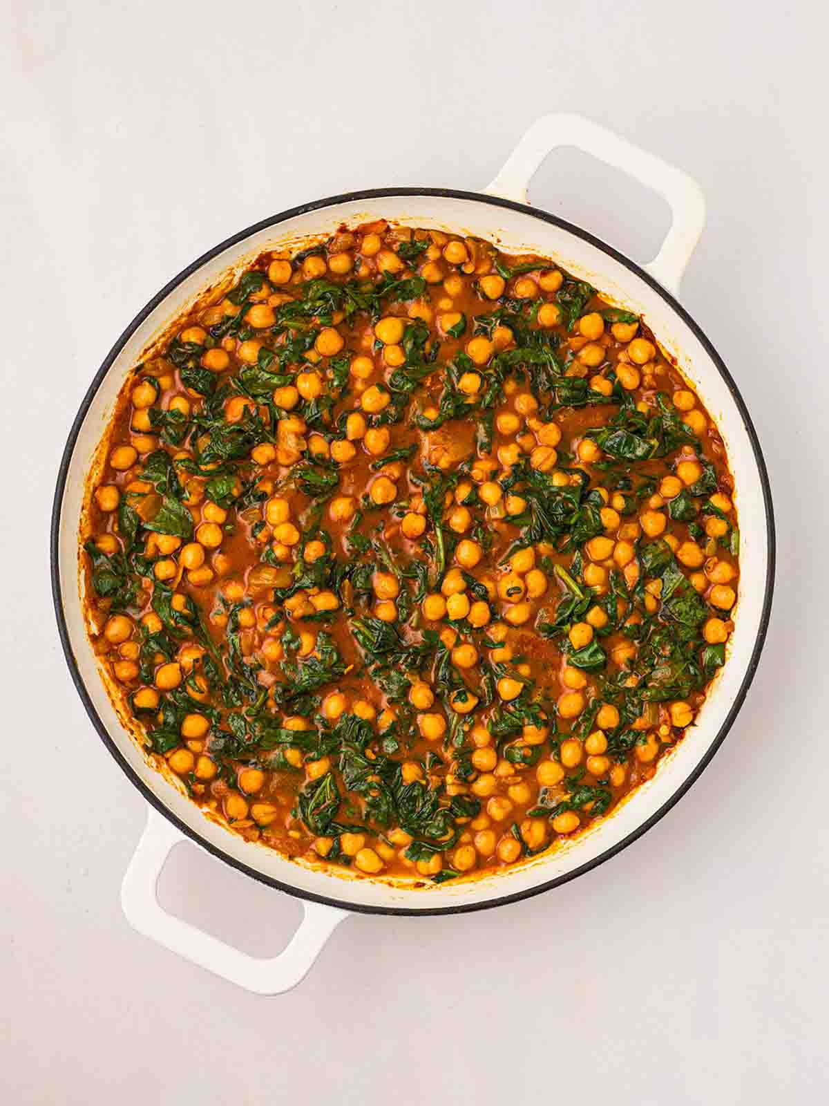 Spinach in a Chickpea Curry, cooked in a white pan.