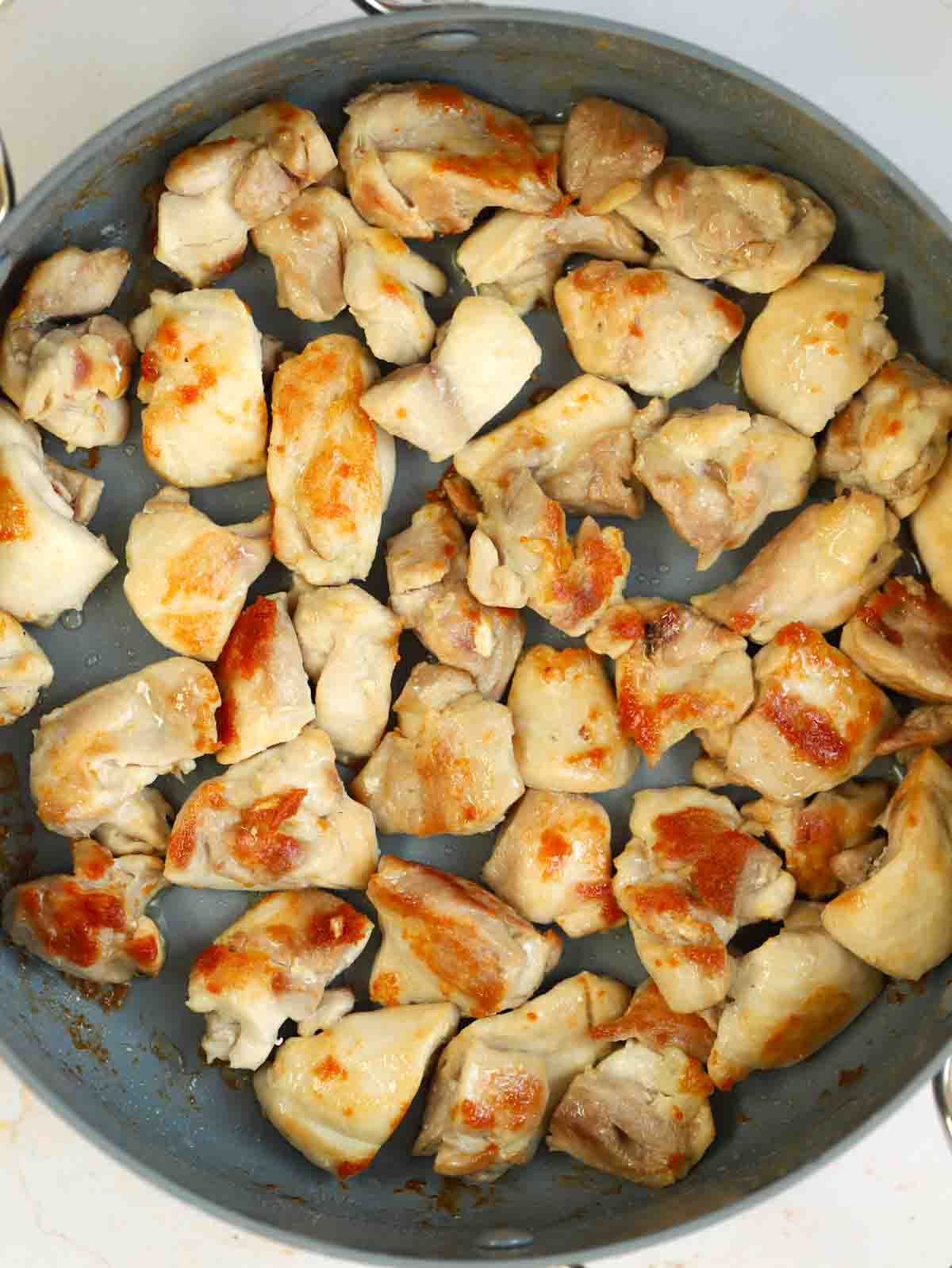 Chicken pieces browning in a pan for step 1 in the recipe for Chicken and Leek Pie.