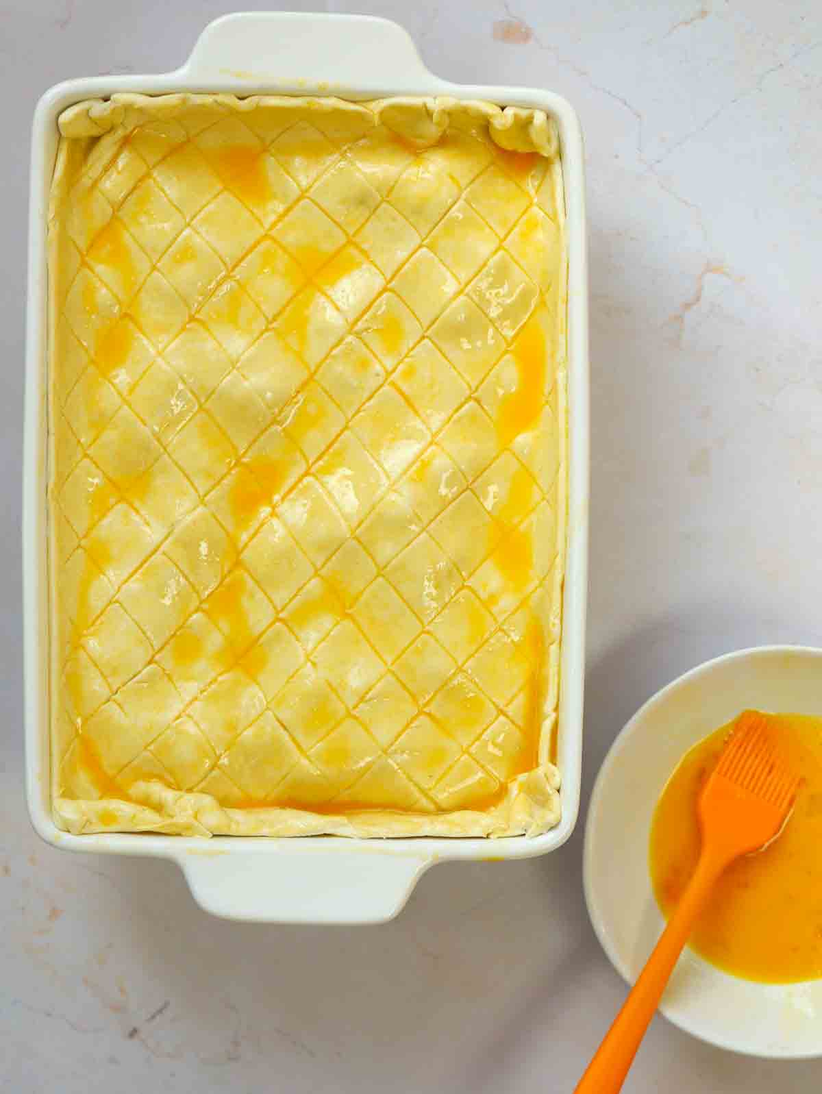 A bird's eye view of an uncooked Chicken and Leek Pie, with egg having been brushed over the top of the pastry.