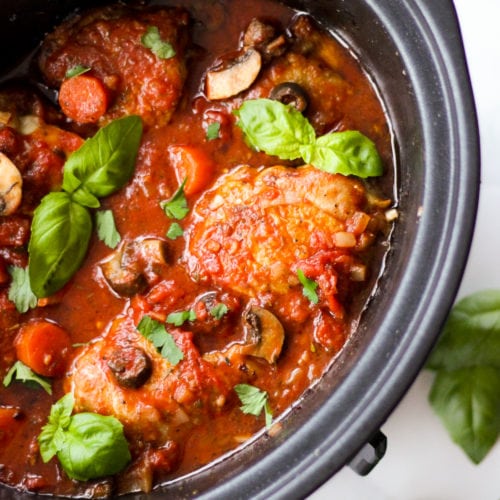 Slow cooker chicken cacciatore in slow cooker sprinkled with basil