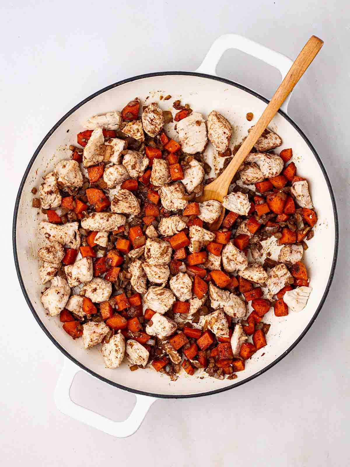 Chicken chunks with carrots and onion in a pan cooking for step 1 in the recipe for Chicken Fried Rice.