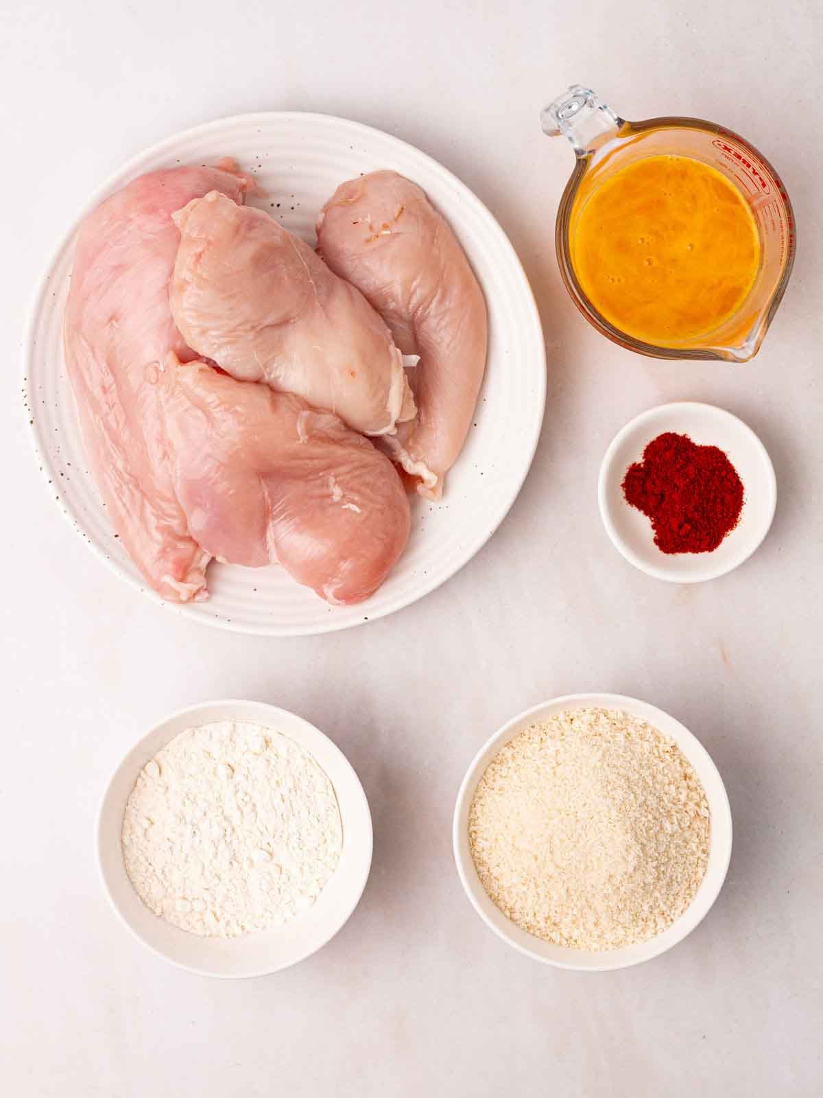 The raw ingredients for making Chicken Goujons laid out on a white counter.