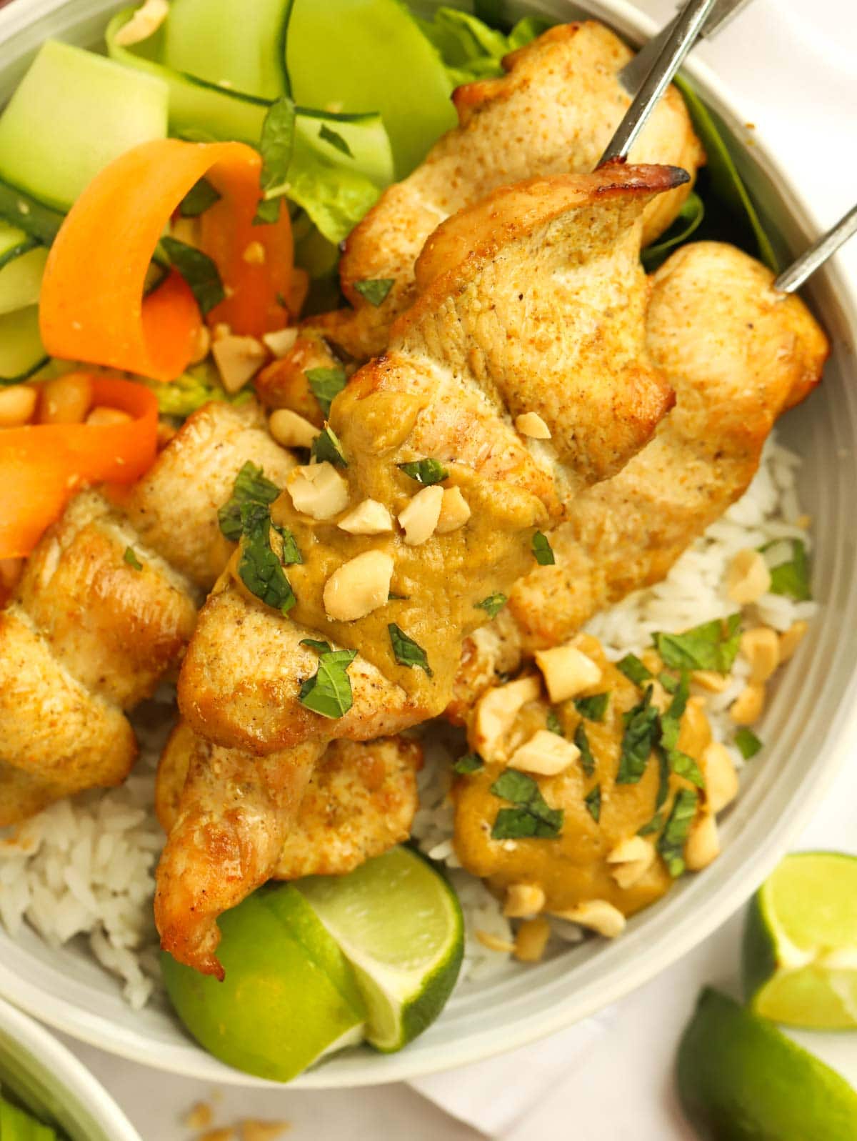 Chicken Satay Skewers topped with peanuts and a side of lime.