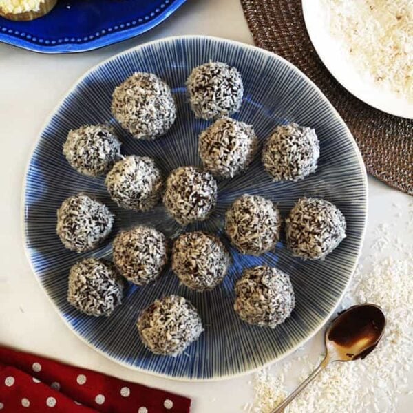 A bird's eye view of a blue plate with homemade chocolate truffles on, coated with desiccated coconut.