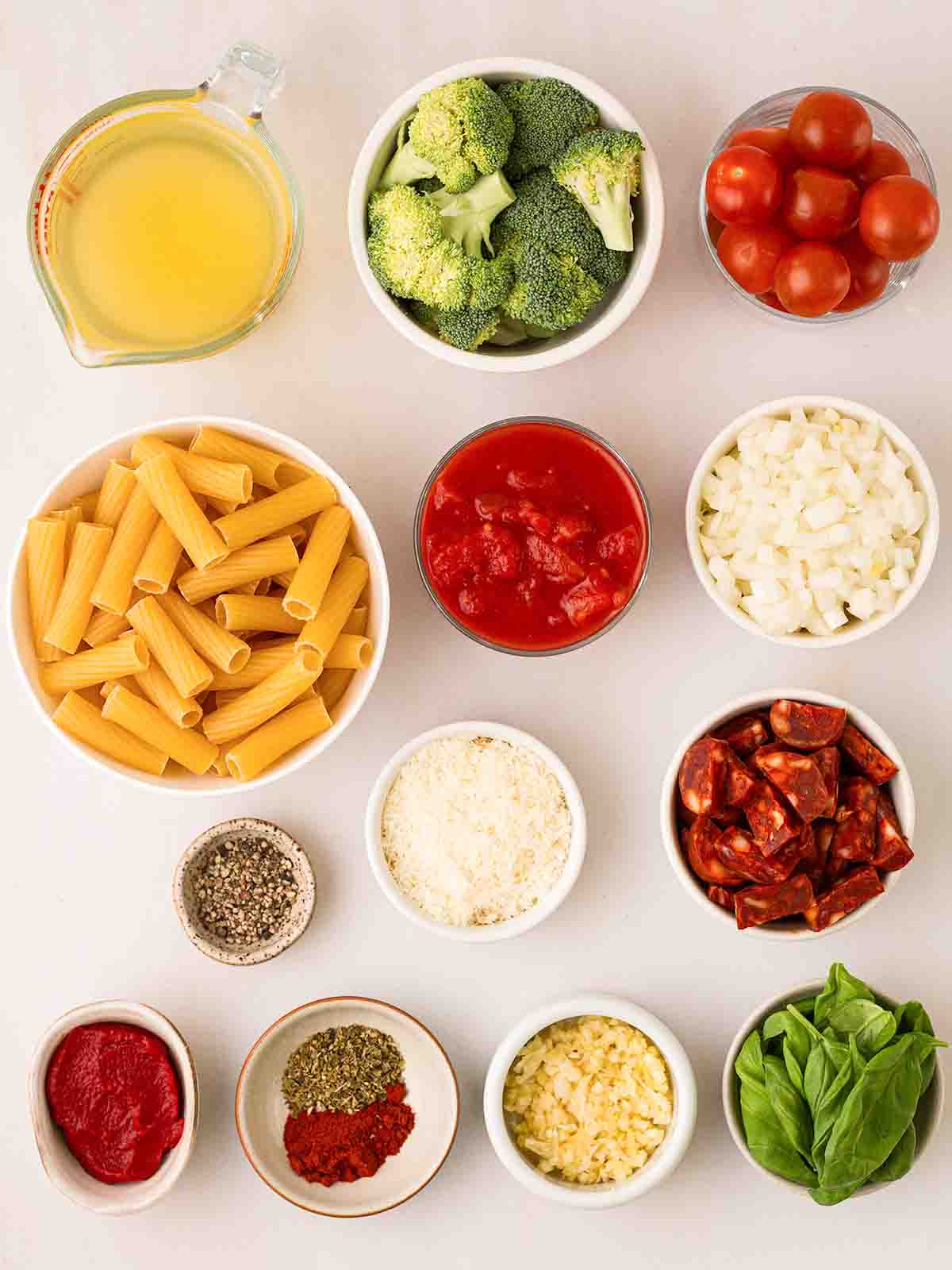 The ingredients for Chorizo Pasta dish laid out in little bowls on a white counter.