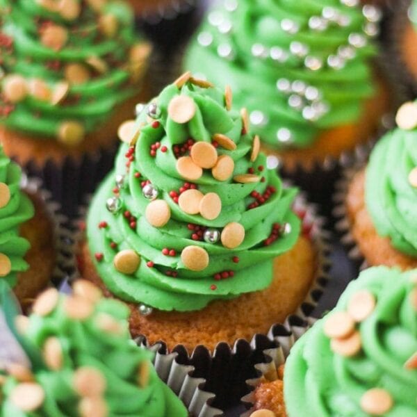 A batch of Christmas Cupcakes with icing shaped like Christmas trees, with sprinkles for baubles.