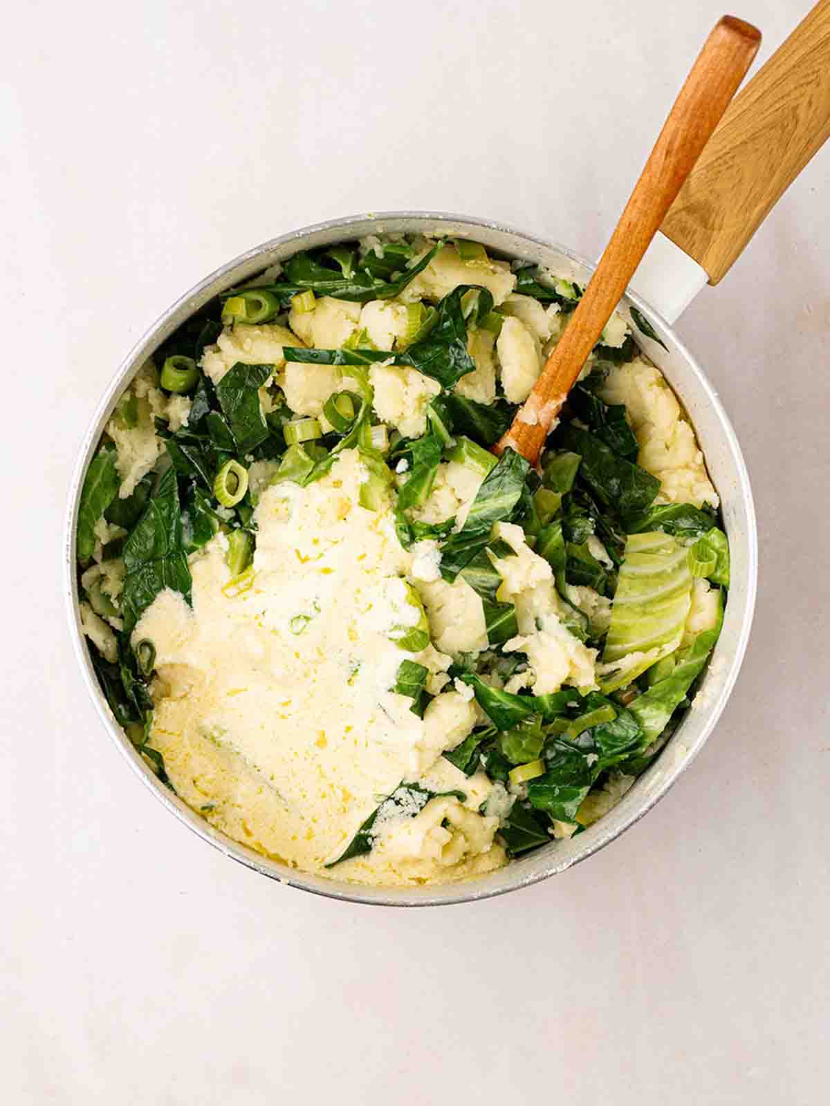 A pan filled with potato and cabbage, with butter and cream on top for step 5 in the recipe for Colcannon.