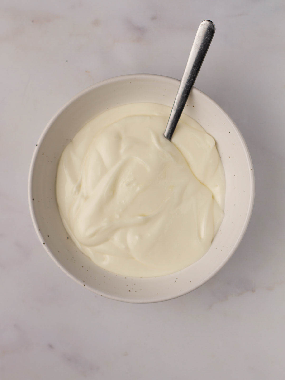 A bowl filled with mascarpone and icing sugar for an icing topping for Courgette Cake.