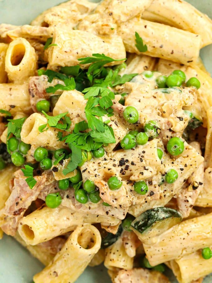 A close up of Philadelphia pasta with peas and bacon in a bowl, garnished with parsley.