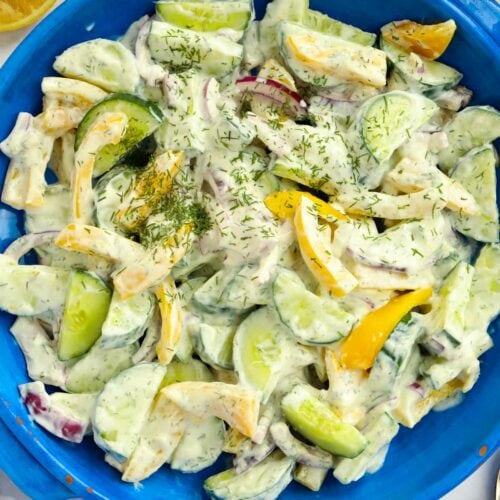 Bowlful of cucumber salad with yellow pepper, red onion and natural yoghurt dressing with dill and garlic.