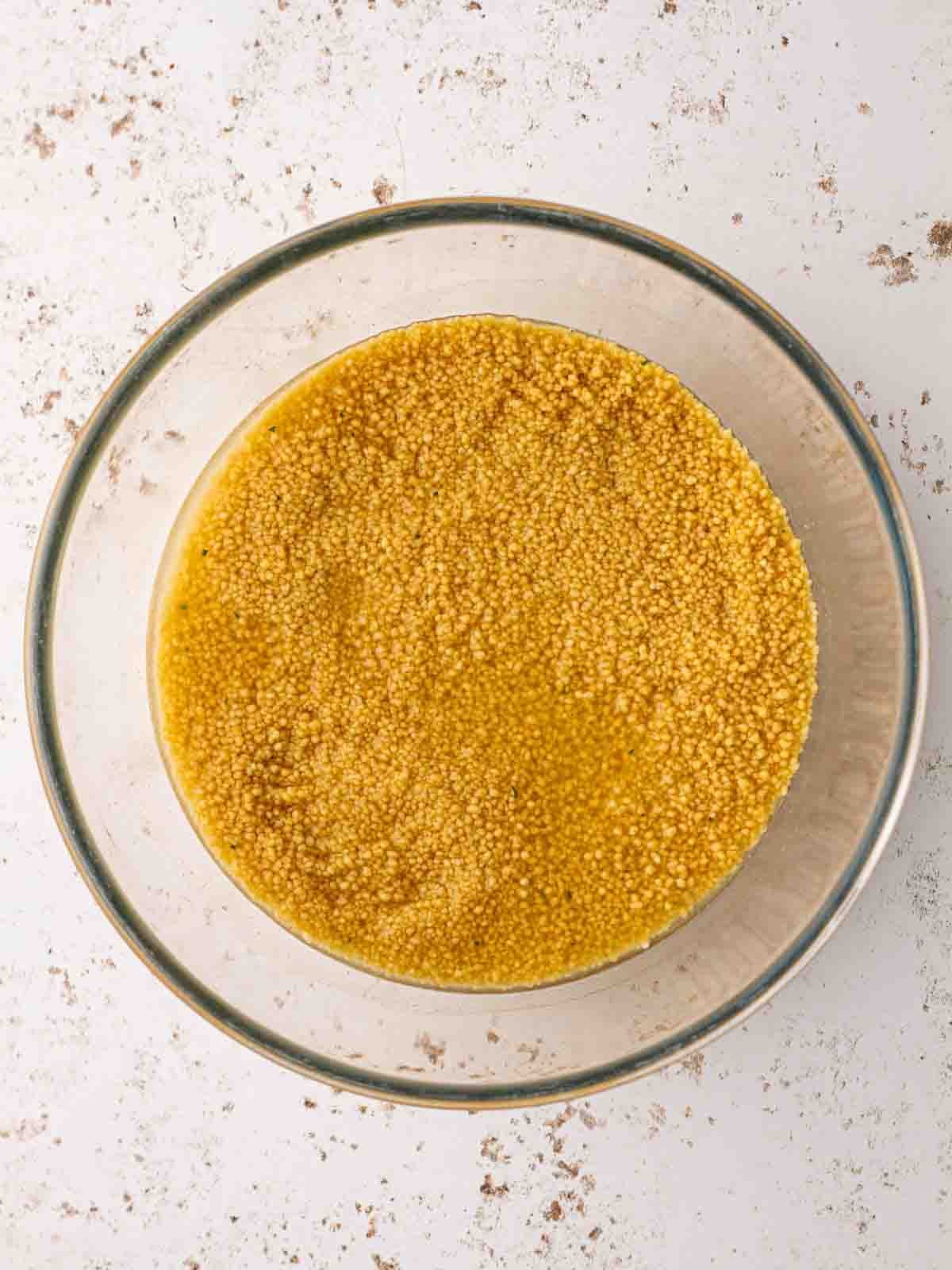 A bowl filled with cous cous and liquid for step 1 in the recipe.