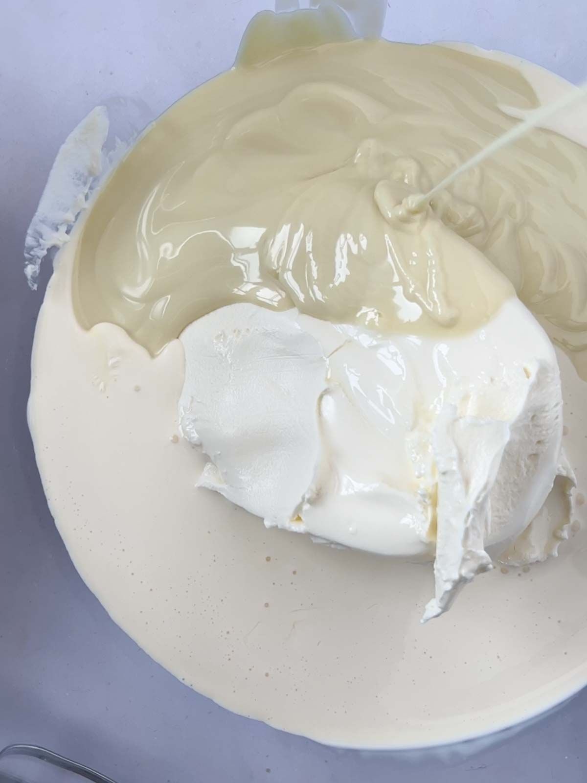 Cream and white chocolate in a bowl, about to be mixed together for the recipe White Chocolate Cheesecake.