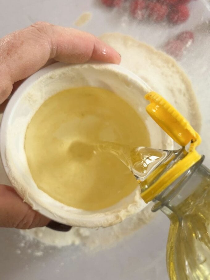 Measuring oil into a yoghurt pot for the recipe for Yoghurt Pot Cake.