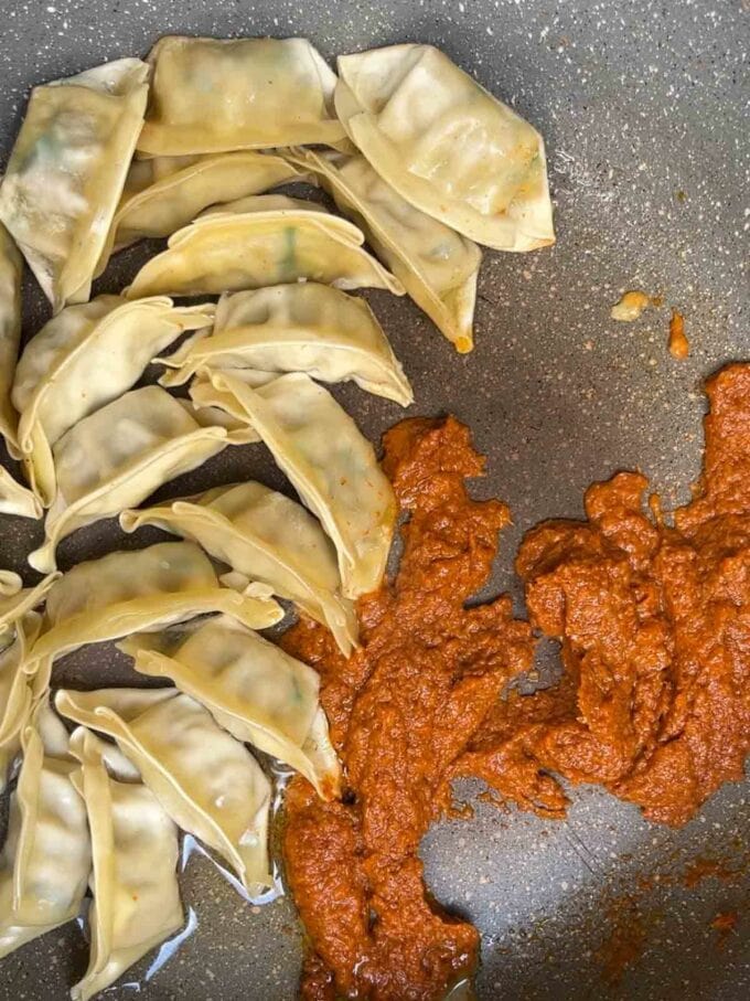 Dumplings and Thai curry paste frying in a pan for step 2 in the recipe for Gyoza Soup.