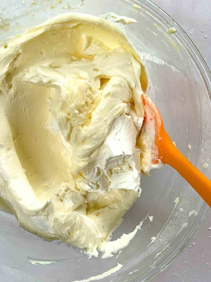 Ingredients for cream cheese icing all mixed together in a glass bowl to make a mixture.