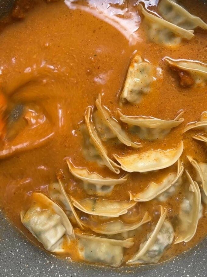 Dumplings cooking in a saucepan for step 3 in the recipe for Gyoza Soup.