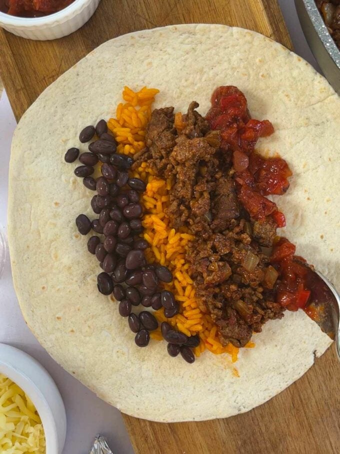 How to make Beef Burritos. Step 3. Add all fillings onto a tortilla.