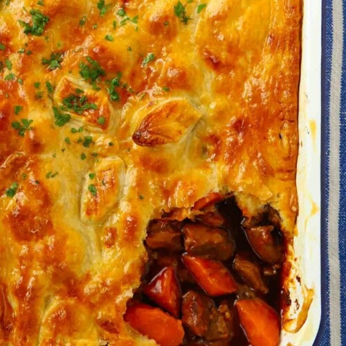 A golden crusty cooked steak pie with a corner missing after being served.