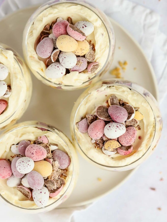 A bird's eye view of Easter Mini Cheesecakes in glass tumblers with Cadbury's Mini Eggs on top.