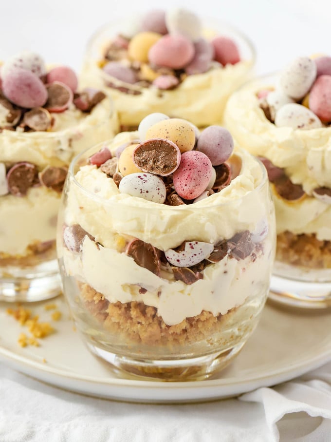 Single serving easter cheesecakes in glass tumblers, on a plate.