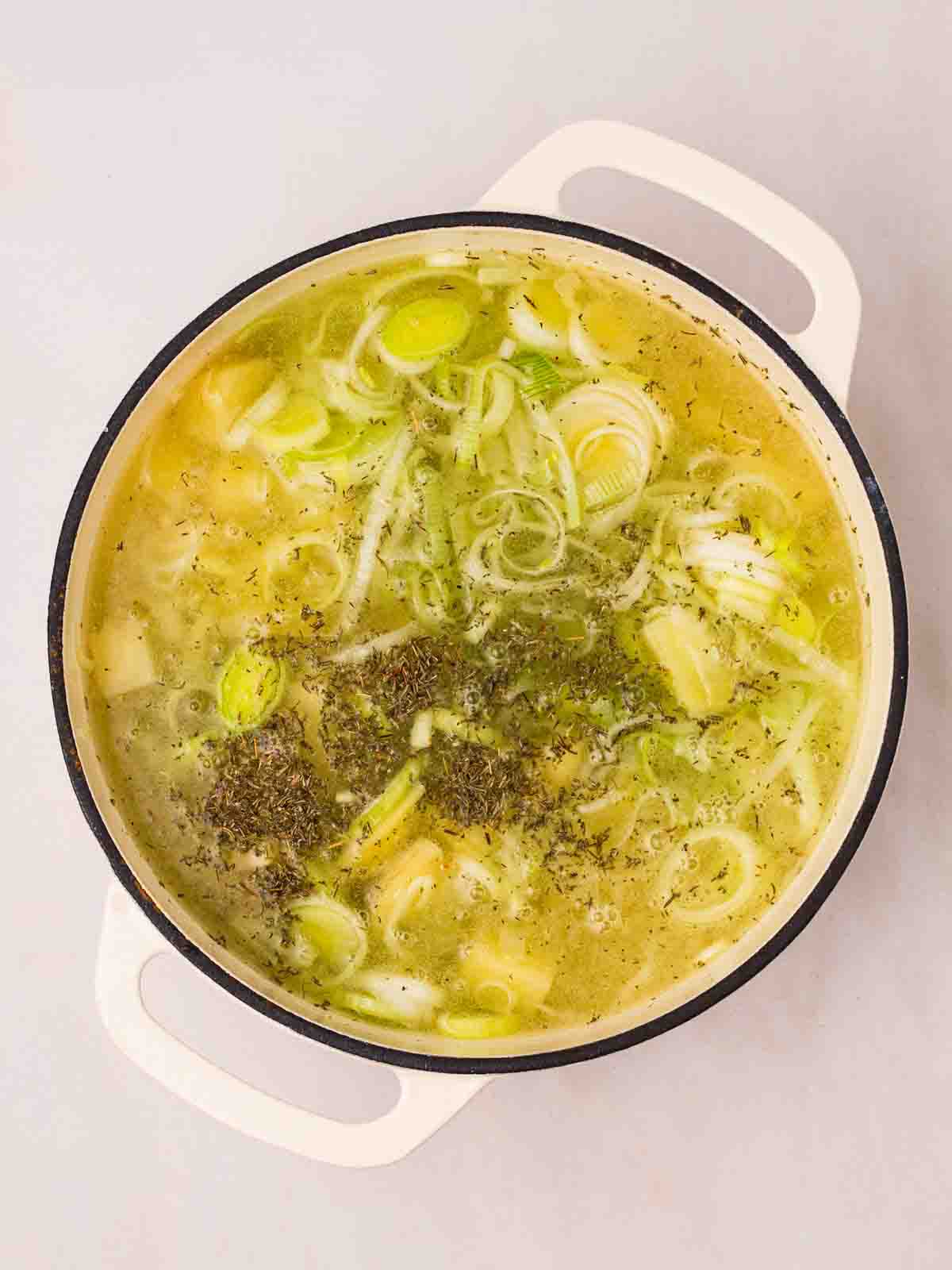 A pan filled with leeks, potato, onions and stock for step 2 in the recipe for Leek and Potato Soup.