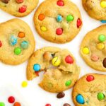 A batch of cookies filled with M&Ms on a white background, ready to eat.