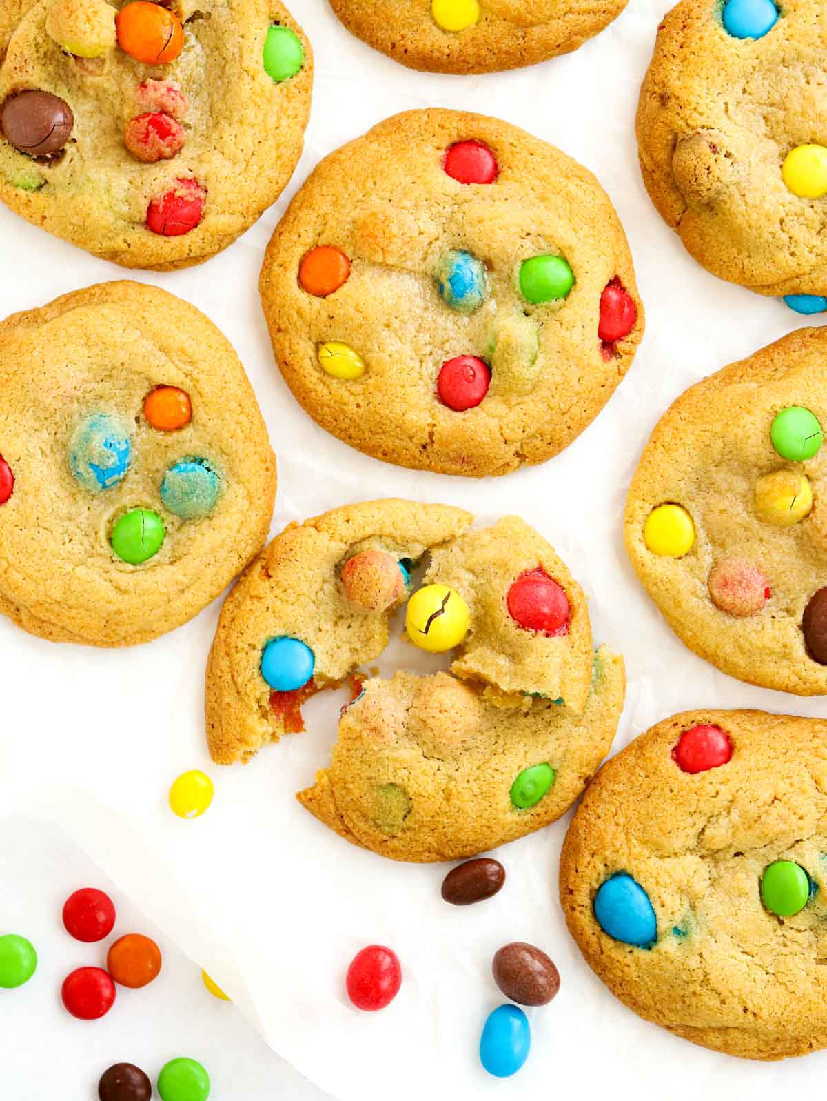 A batch of homemade cookies on a white background, filled with Smarties.