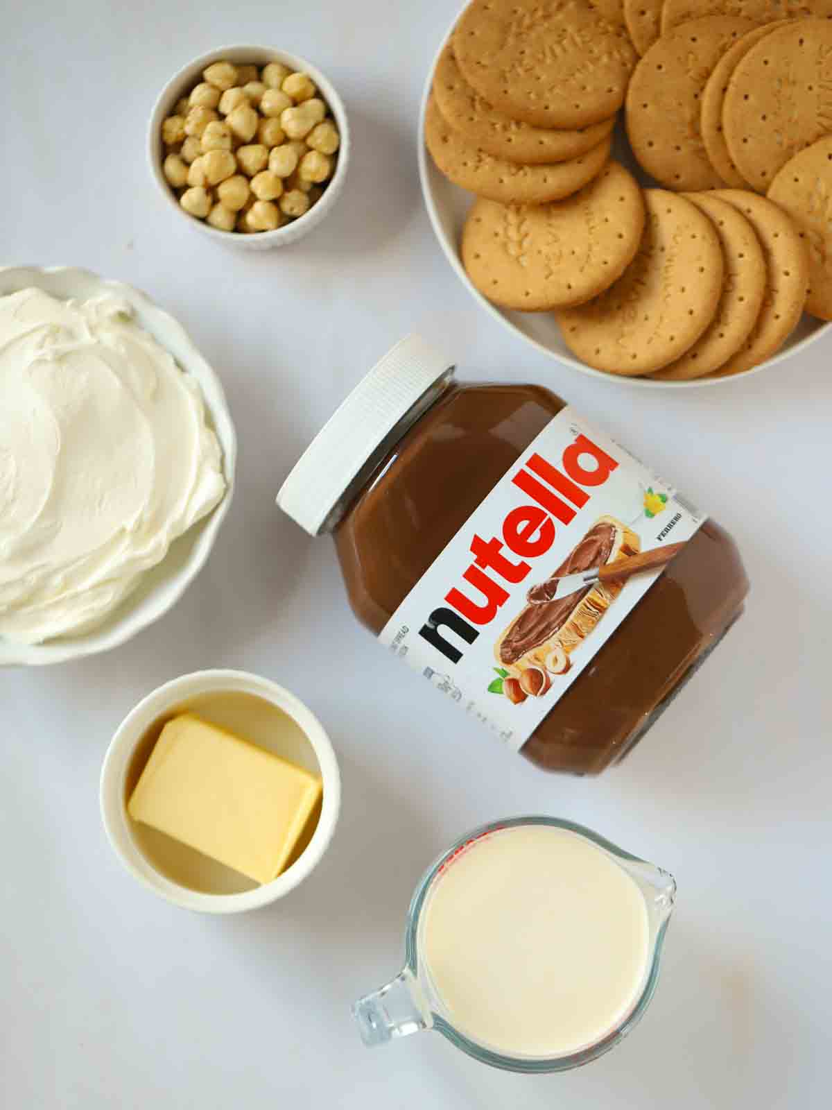 The ingredients to make a Nutella Cheesecake laid out on a white counter.