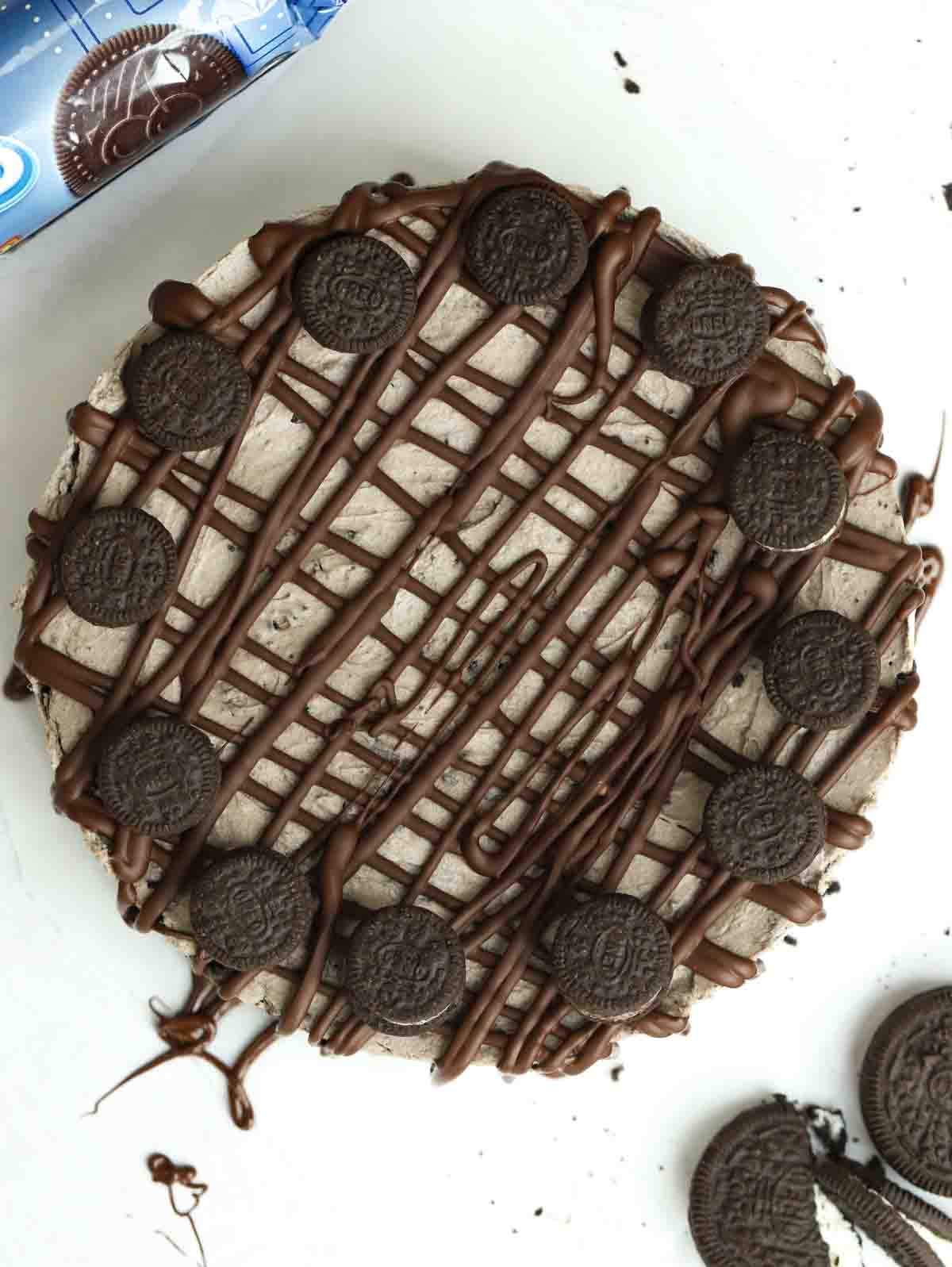 A bird's eye view of an Oreo Cheesecake, decorated with melted chocolate and mini Orea cookies.