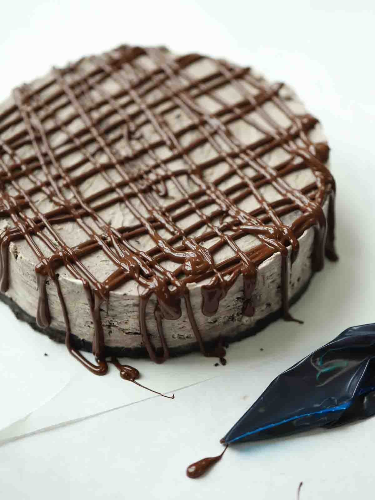 An Oreo Cheesecake decorated with melted chocolate.