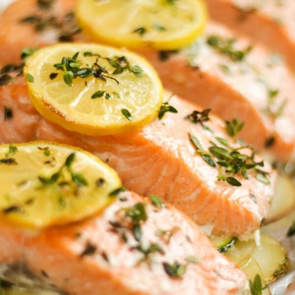A line of baked salmon with sliced lemon and herbs on top, fresh out of the oven.