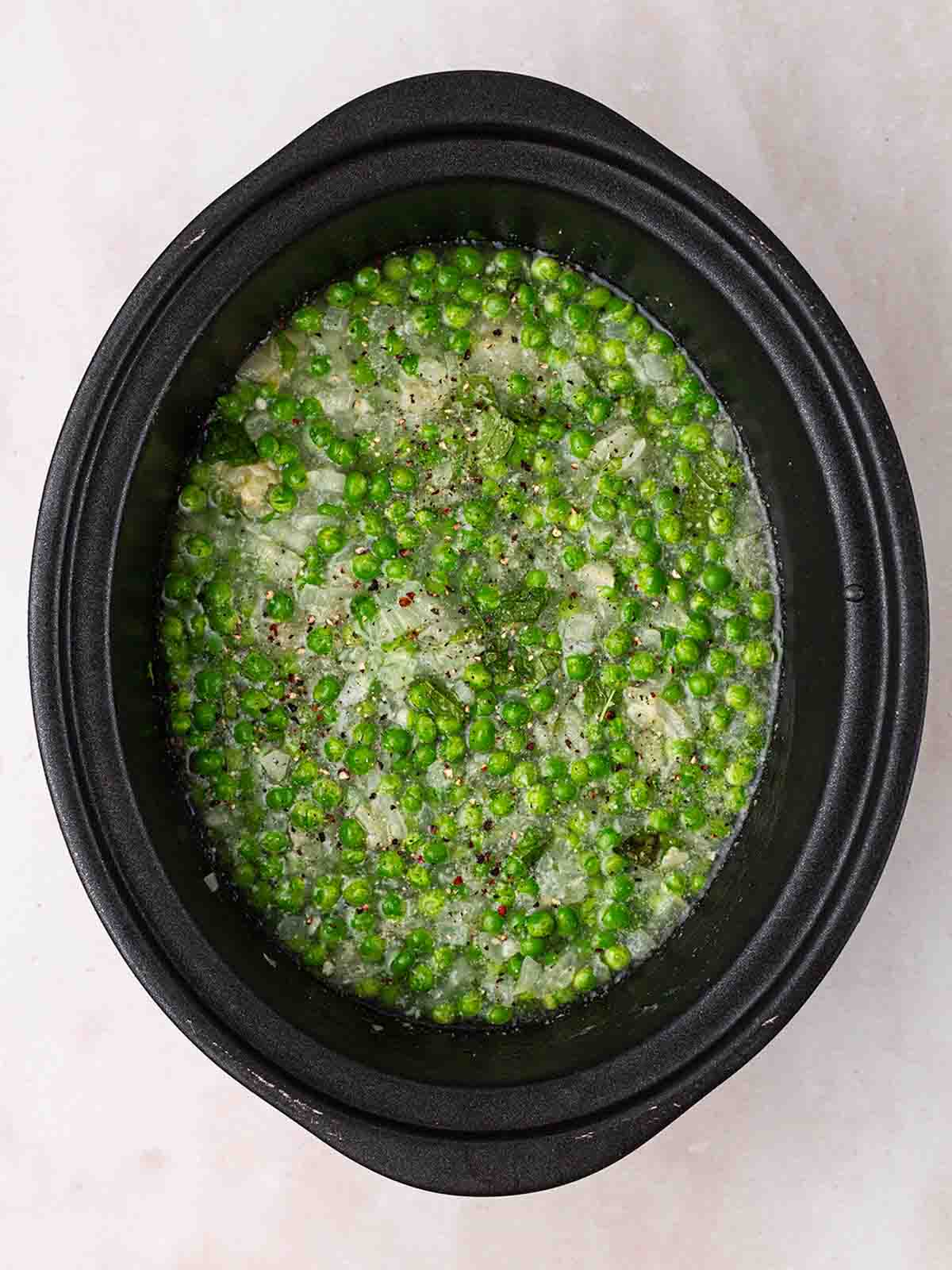 A slow cooker with lots of peas for step 2 in the process for Pea and Ham Soup.
