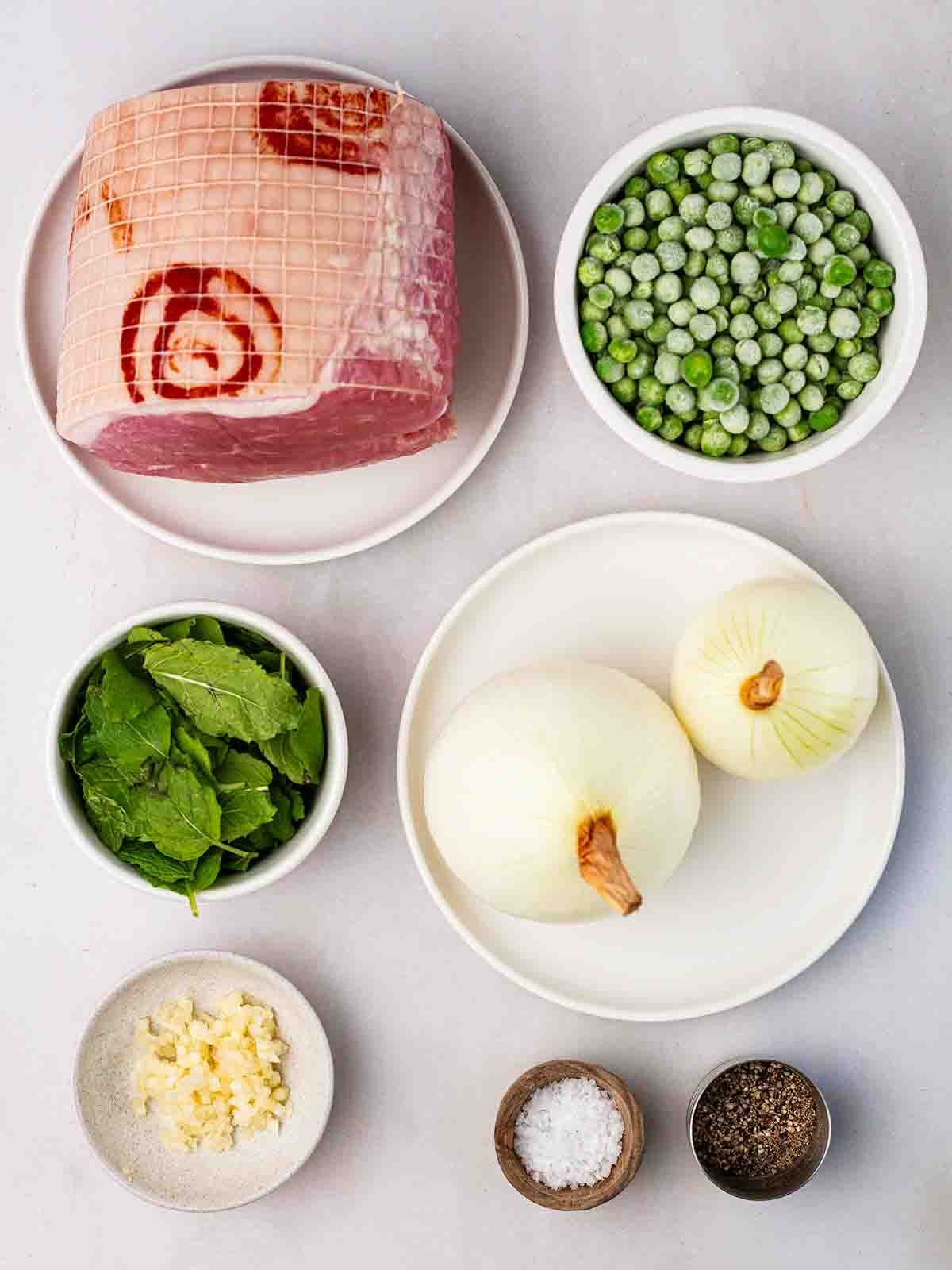 The raw ingredients for Pea and Ham Soup laid out on a counter top in bowls.