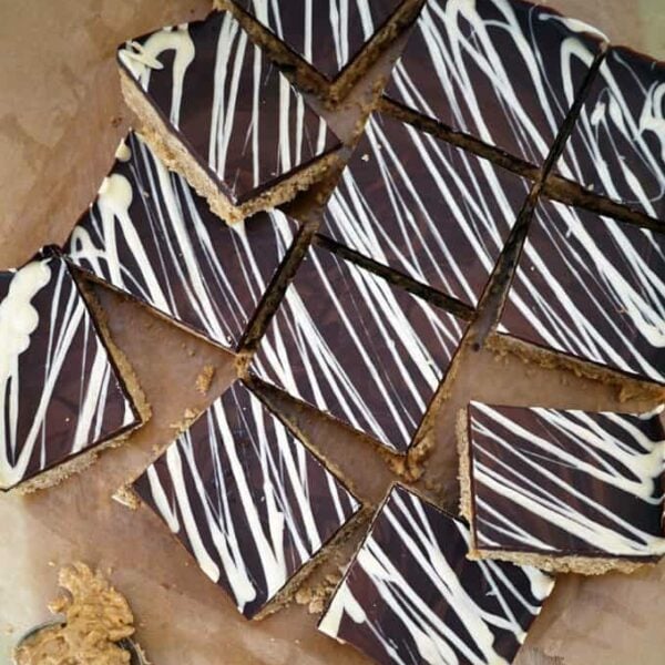 A slab of peanut butter bars cut into 12 squares on a chopping board.
